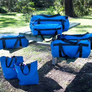 Collection of canvas blue duffle bag and shopping and beach bags on a park picnic bench
